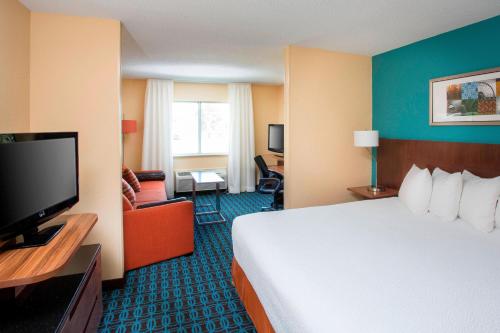 a hotel room with a bed and a flat screen tv at Fairfield Inn & Suites by Marriott Terre Haute in Terre Haute