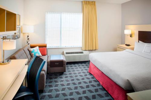 a hotel room with a bed and a chair and a window at TownePlace Suites by Marriott Phoenix Goodyear in Goodyear