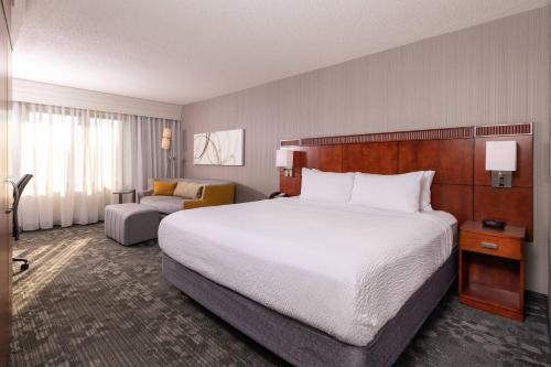 a hotel room with a large bed and a chair at Courtyard by Marriott Newark-University of Delaware in Newark