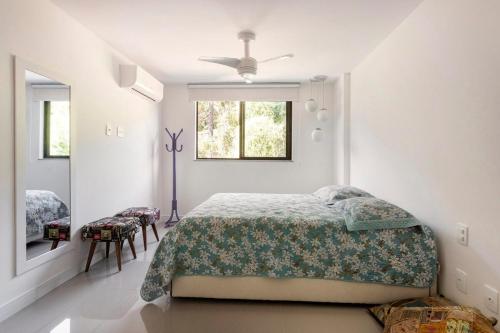 a white bedroom with a bed and a window at Apto Itaipava, piscina borda infinita, montanha in Itaipava