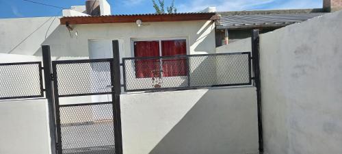 a white house with a fence and a window at Departamento Alicia in General Roca