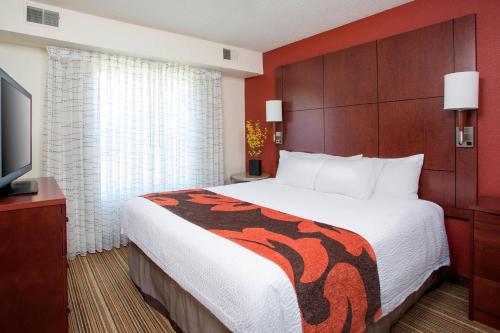 a hotel room with a bed and a flat screen tv at Residence Inn Rockford in Rockford