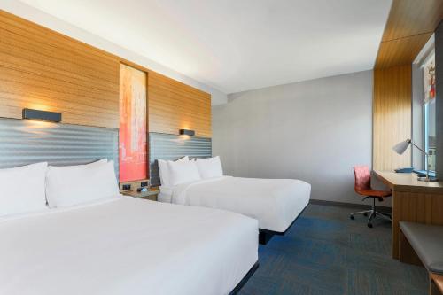 a hotel room with two beds and a desk at Aloft Phoenix Airport in Phoenix