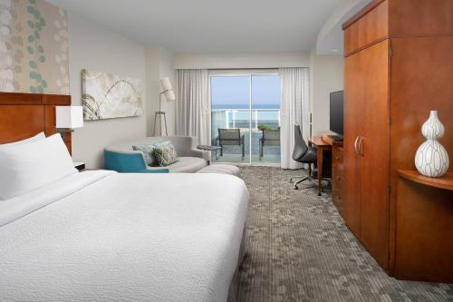 Courtyard by Marriott Ocean City Oceanfront في آوشين سيتي: غرفة فندقية فيها سرير ومكتب وتلفزيون