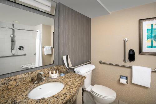 a bathroom with a sink and a toilet and a mirror at Courtyard by Marriott Ocean City Oceanfront in Ocean City