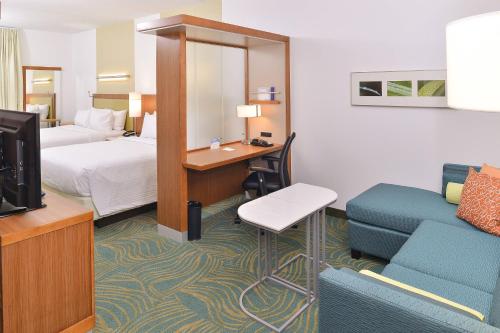 a hotel room with a bed and a tv and a couch at SpringHill Suites by Marriott Raleigh Cary in Cary