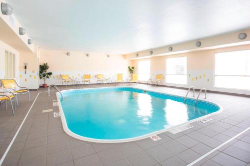 Una piscina en una habitación grande con sillas y mesas. en Fairfield Inn & Suites Oshkosh en Oshkosh