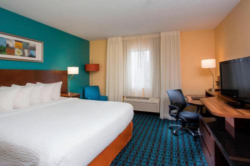 a hotel room with a bed and a desk and a television at Fairfield Inn & Suites Oshkosh in Oshkosh