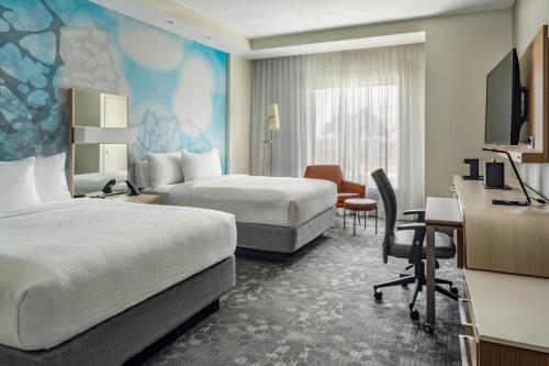 CanaにあるCourtyard by Marriott Port St. Lucie Traditionのベッド2台とデスクが備わるホテルルームです。