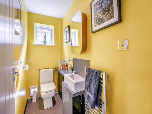 a yellow bathroom with a sink and a toilet at Albany House in Seaford
