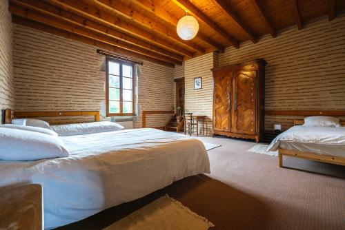 1 dormitorio con 2 camas y pared de madera en La Maison du Turc - Piscine partagée, en Le Mas-dʼAgenais