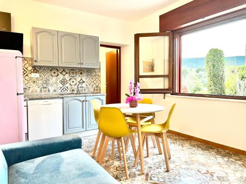 a kitchen with a table and yellow chairs in a room at Le Corti Sarde Countryside in Bari Sardo