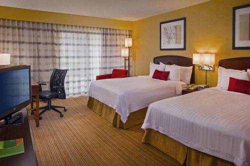 a hotel room with two beds and a flat screen tv at Courtyard by Marriott Richmond Northwest in Henrico