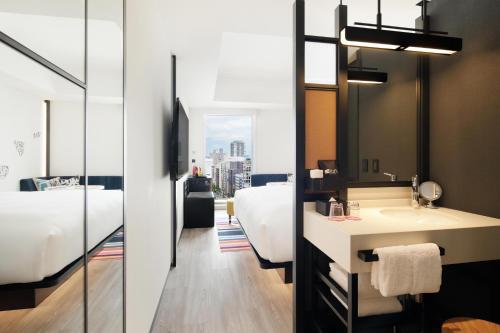 a bathroom with a sink and a bed and a mirror at Aloft Tokyo Ginza in Tokyo