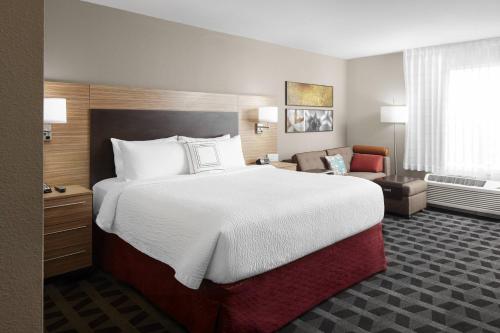 a hotel room with a large bed and a chair at TownePlace Suites by Marriott Tampa South in Tampa