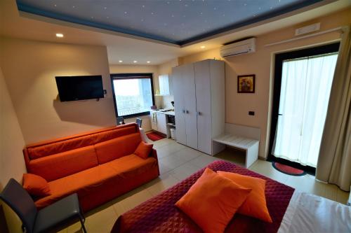 een woonkamer met een oranje bank en een televisie bij B&B Dimora dell' Etna in Milo