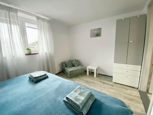 a bedroom with a blue bed and a chair at Apartmán Eden in Bystrzyca
