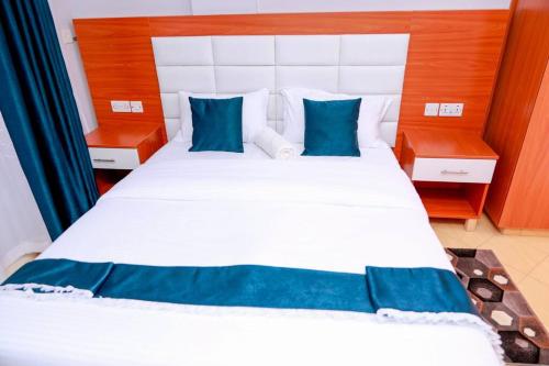 um quarto com uma grande cama branca com almofadas azuis em Luxe Furnished Apartments Unit 3 em Meru