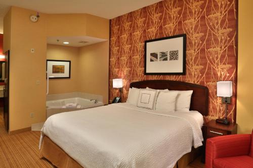 a hotel room with a bed and a red chair at Courtyard by Marriott Springfield Airport in Springfield