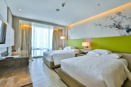 a hotel room with two beds and a green wall at Courtyard by Marriott Iloilo in Iloilo City