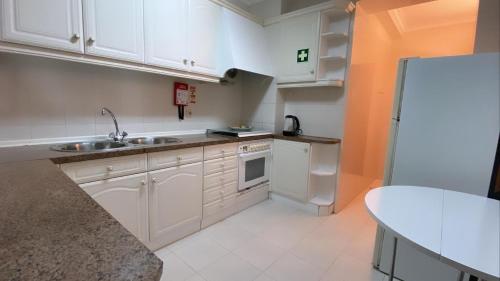 uma cozinha com armários brancos, um lavatório e um frigorífico em Ocean and River Apartment em Torreira