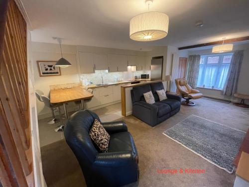 a living room with two couches and a kitchen at Corner Cottage in Bewdley