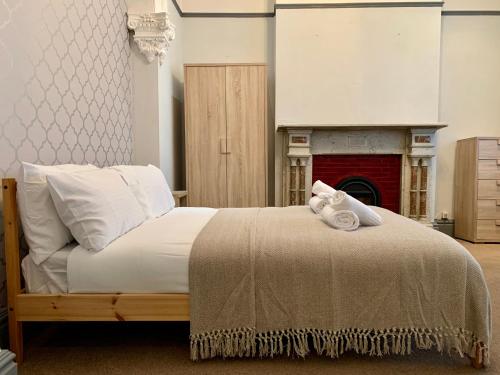 a bedroom with a bed with white pillows and a fireplace at Somerford Place - 6 Beds - Sleeps 12 - Parks 2-3 cars/vans in Willenhall