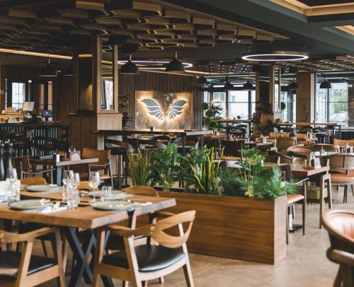 ein Restaurant mit Tischen, Stühlen und Pflanzen in der Unterkunft Bristol Hotel Podgorica in Podgorica