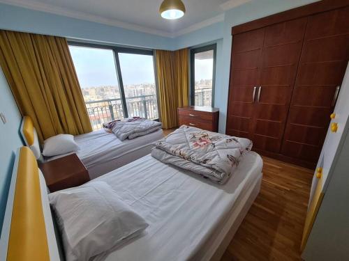 a bedroom with two beds and a large window at Luxury Hotel Apartment at Grand Plaza, San Stefano with Access to fee-based facilities at Four Seasons in Alexandria