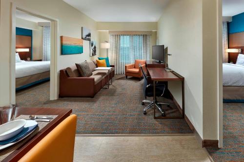 a hotel room with a desk and a living room at Residence Inn by Marriott San Diego Chula Vista in Chula Vista
