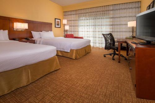 a hotel room with two beds and a desk with a television at Courtyard Williamsburg - Busch Gardens in Williamsburg