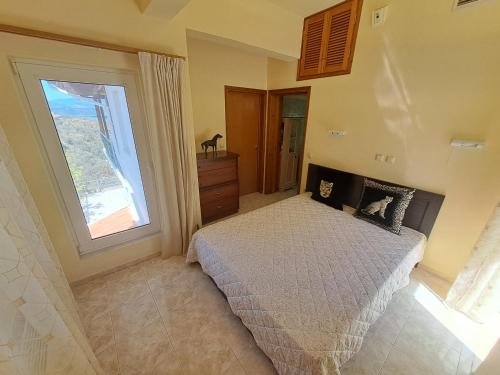 a bedroom with a bed and a large window at GEORGE'S VILLA in Galatas