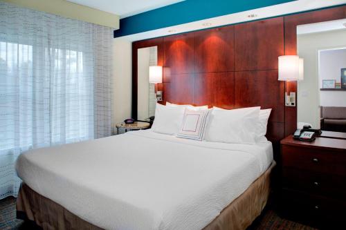 a bedroom with a large bed with a wooden headboard at Residence Inn by Marriott Richmond Chester in Woodvale