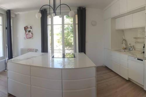 a white kitchen with a large island in the middle at Logement à 30min de la défense avec piscine privative in Conflans-Sainte-Honorine