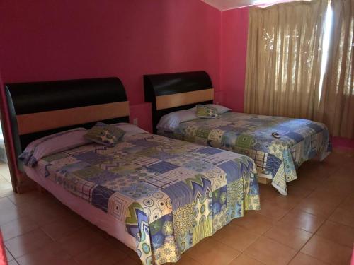 2 Betten in einem Zimmer mit rosa Wänden in der Unterkunft Hermosa Casa Ikal en Acapulco in Barra de Coyuca