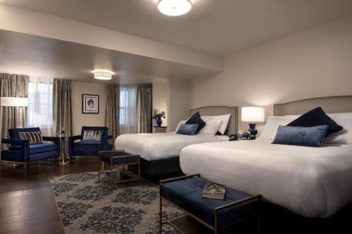 a hotel room with two beds and blue chairs at Seven Gables Inn, St Louis West, a Tribute Portfolio Hotel in Saint Louis