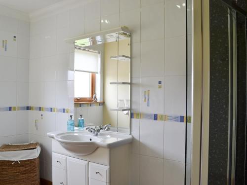 a white bathroom with a sink and a mirror at Sandy Beach in Nairn