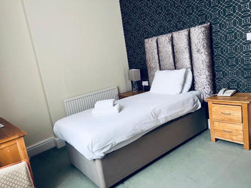 a small bedroom with a bed and a night stand at Merrion Hotel in Llandudno