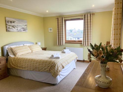 een slaapkamer met een bed en een vaas met bloemen op een tafel bij Sandy Beach in Nairn