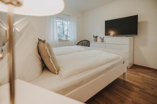 a white bedroom with a couch and a tv at Ferienwohnung Weidenblick in Varel