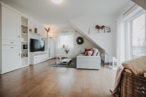 a white living room with a couch and a tv at Ferienwohnung Weidenblick in Varel