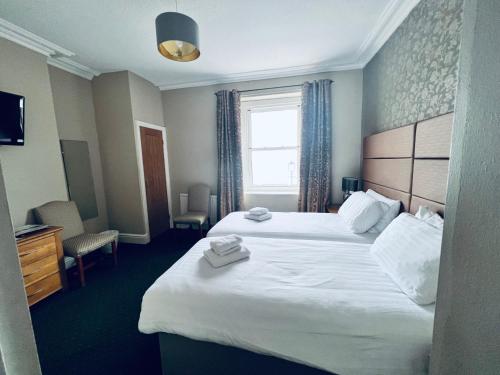 a hotel room with two beds and a window at Merrion Hotel in Llandudno