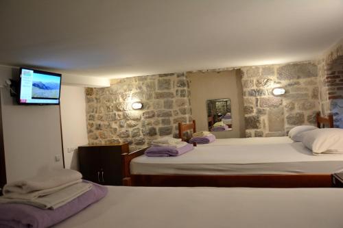 a bedroom with two beds and a tv on the wall at Montenegro Hostel B&B Kotor in Kotor