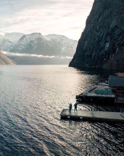 two people standing on a dock in a body of water at Undredal Fjord Apartments in Undredal