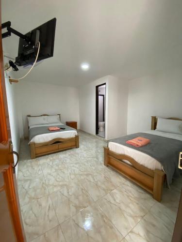 a room with two beds and a tv on the wall at Hotel la Victoria in San Roque