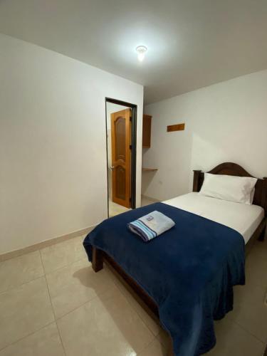 a bedroom with a bed with a blue blanket and a mirror at Hotel la Victoria in San Roque