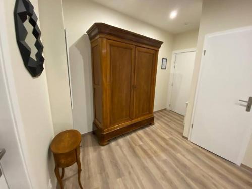 a hallway with a wooden cabinet and a chair at Duplex By Aurelle 2 in Schiltigheim