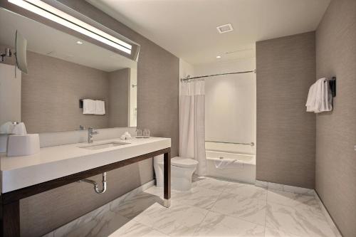 a bathroom with a sink and a toilet and a mirror at Courtyard by Marriott Montreal Brossard in Brossard