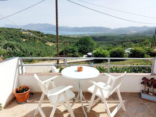 einen weißen Tisch und Stühle auf einem Balkon mit Aussicht in der Unterkunft Jacob's Sunrise cottage in Kissamos