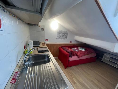 Habitación pequeña con sofá rojo y lavabo. en Apartment A.C.& G.O. Milan, en Milán